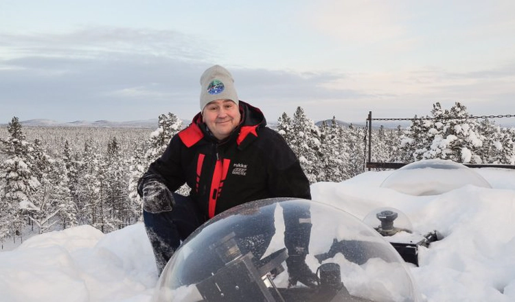 Urban Brändström på observatoriets tak där kameror syns under glaskupoler, med ett vintrigt landskap i bakgrunden.