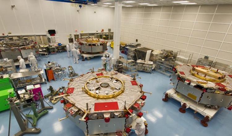 MMS-satelliterna på golvet i ett större renrum, tillsammans med skyddsklädda ingenjörer MMS-satelliterna på golvet i ett större renrum, tillsammans med skyddsklädda ingenjörer