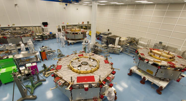 MMS-satelliterna på golvet i ett större renrum, tillsammans med skyddsklädda ingenjörer MMS-satelliterna på golvet i ett större renrum, tillsammans med skyddsklädda ingenjörer