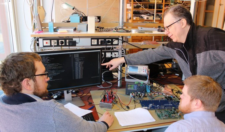 Forskningsingenjörerna Martin Berglund, Dan Ohlsson och Walter Puccio i elektroniklabbet i Uppsala med elektronikkort.