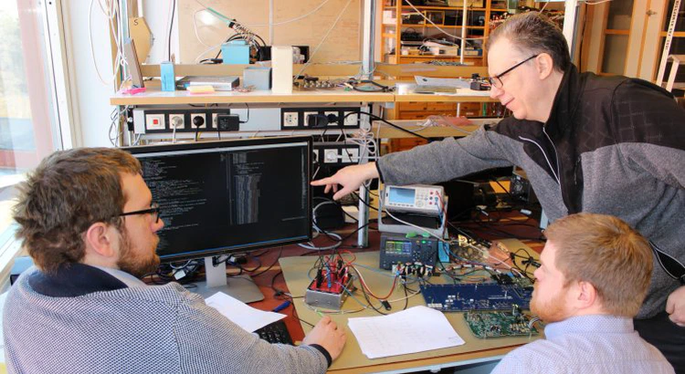 Forskningsingenjörerna Martin Berglund, Dan Ohlsson och Walter Puccio i elektroniklabbet i Uppsala med elektronikkort.
