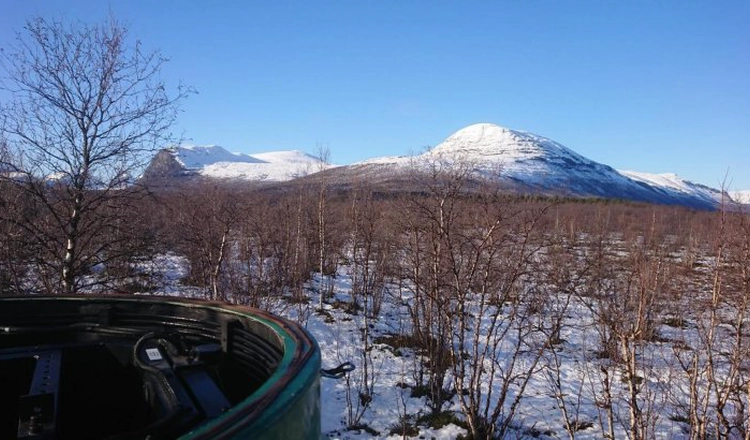 Mätstationen i Nikkaluokta med borttagen kupol i förgrunden, med snötäckta Kebnekaisefjällen i bakgunden