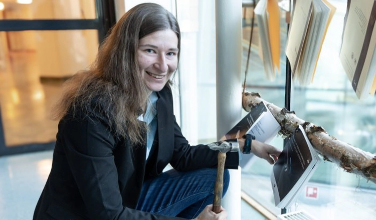 Anja Möslinger holding a hammer in front of her nailed thesis Anja Möslinger holding a hammer in front of her nailed thesis