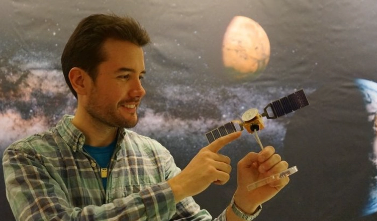 Robin ramstad pekar på en miniatyrmodell av Mars Express som han håller i handen