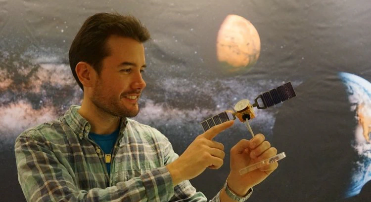 Robin ramstad pekar på en miniatyrmodell av Mars Express som han håller i handen