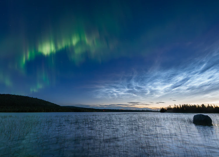 Norrsken och nattlysande moln över sjö