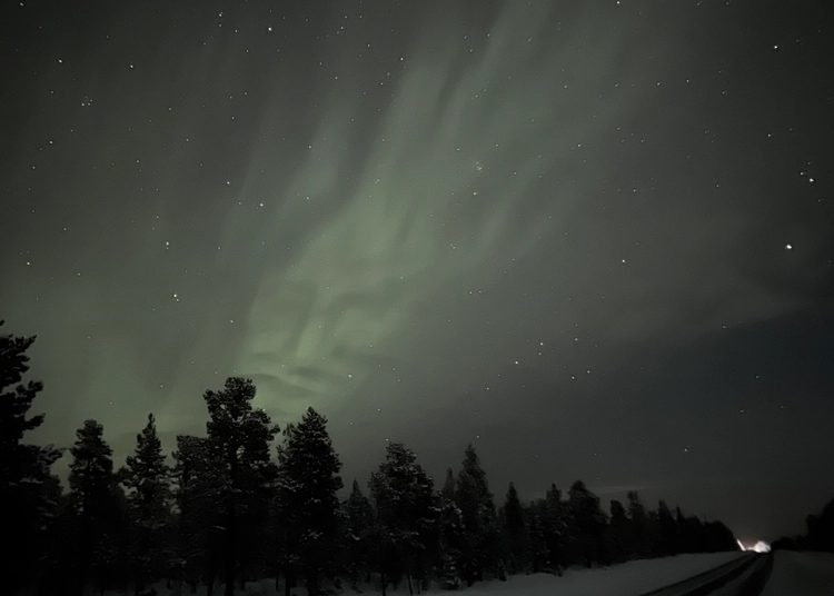 Norrsken i form av ett ansikte över bilväg