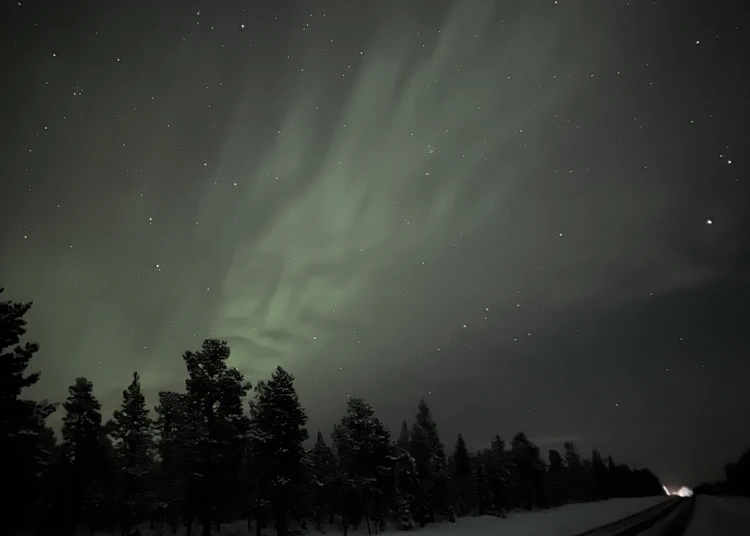Norrsken i form av ett ansikte över bilväg